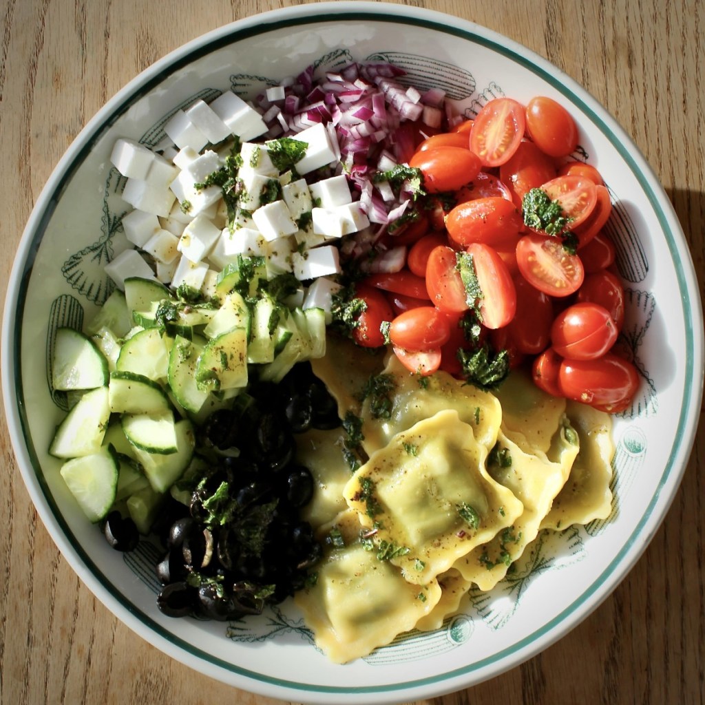 Greek salad in a large pasta bowl with ravioli